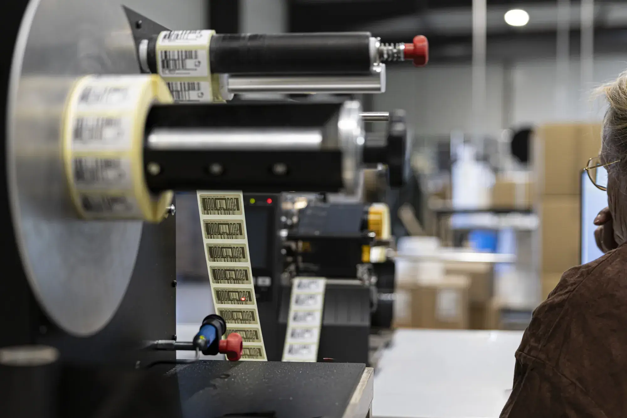 Opératrice suivant le défilement d'une bande d'étiquettes RFID sur l'enrouleur